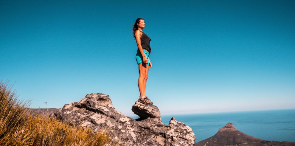 Woman in Black Top and Blue Shorts on Stone Under Blue Sky